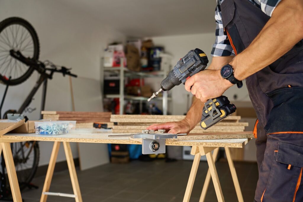 Carpenter drilling wooden panel using jig tool for precise holes
